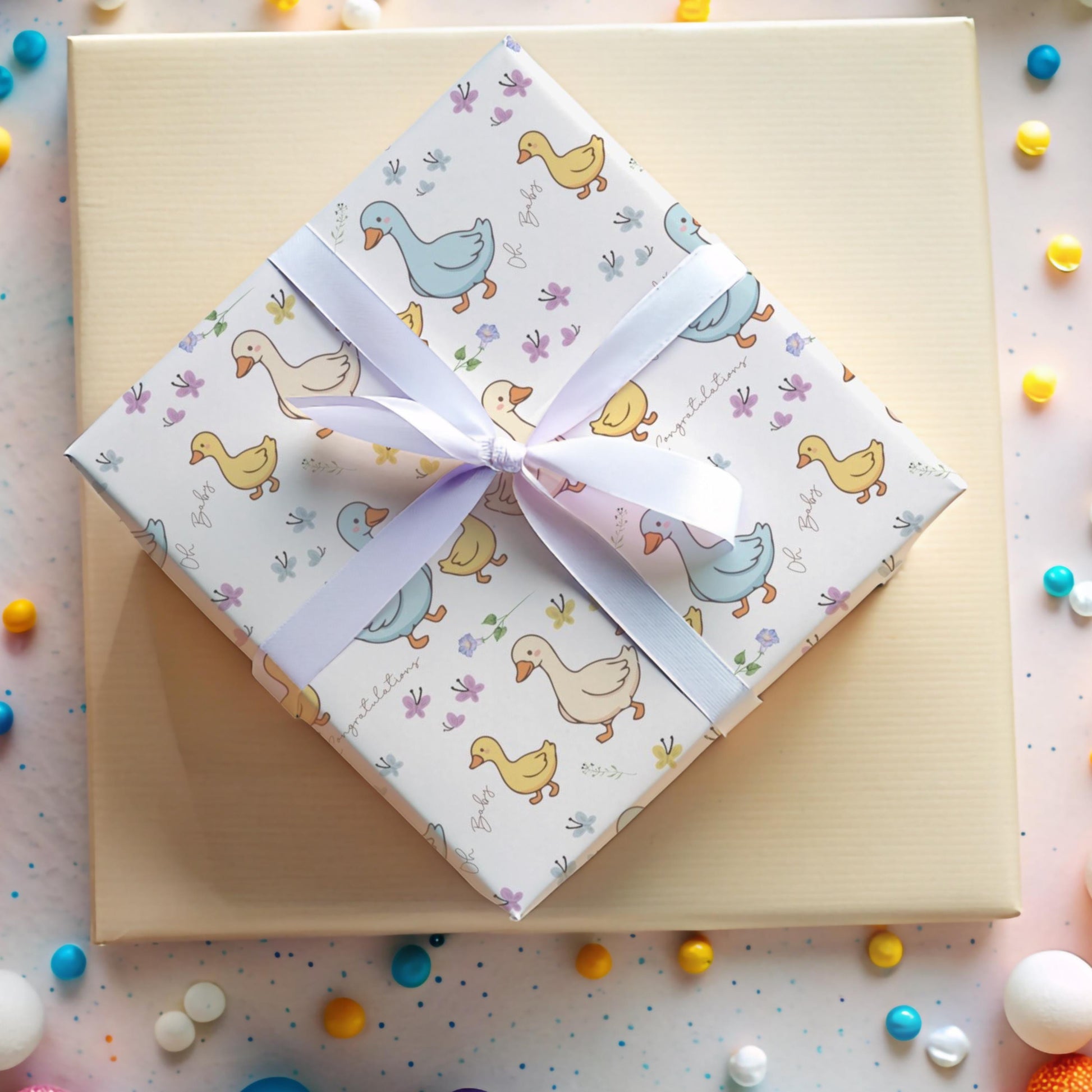 Cute duck baby shower wrapping paper with pastel ducklings and flowers wrapped around gift boxes