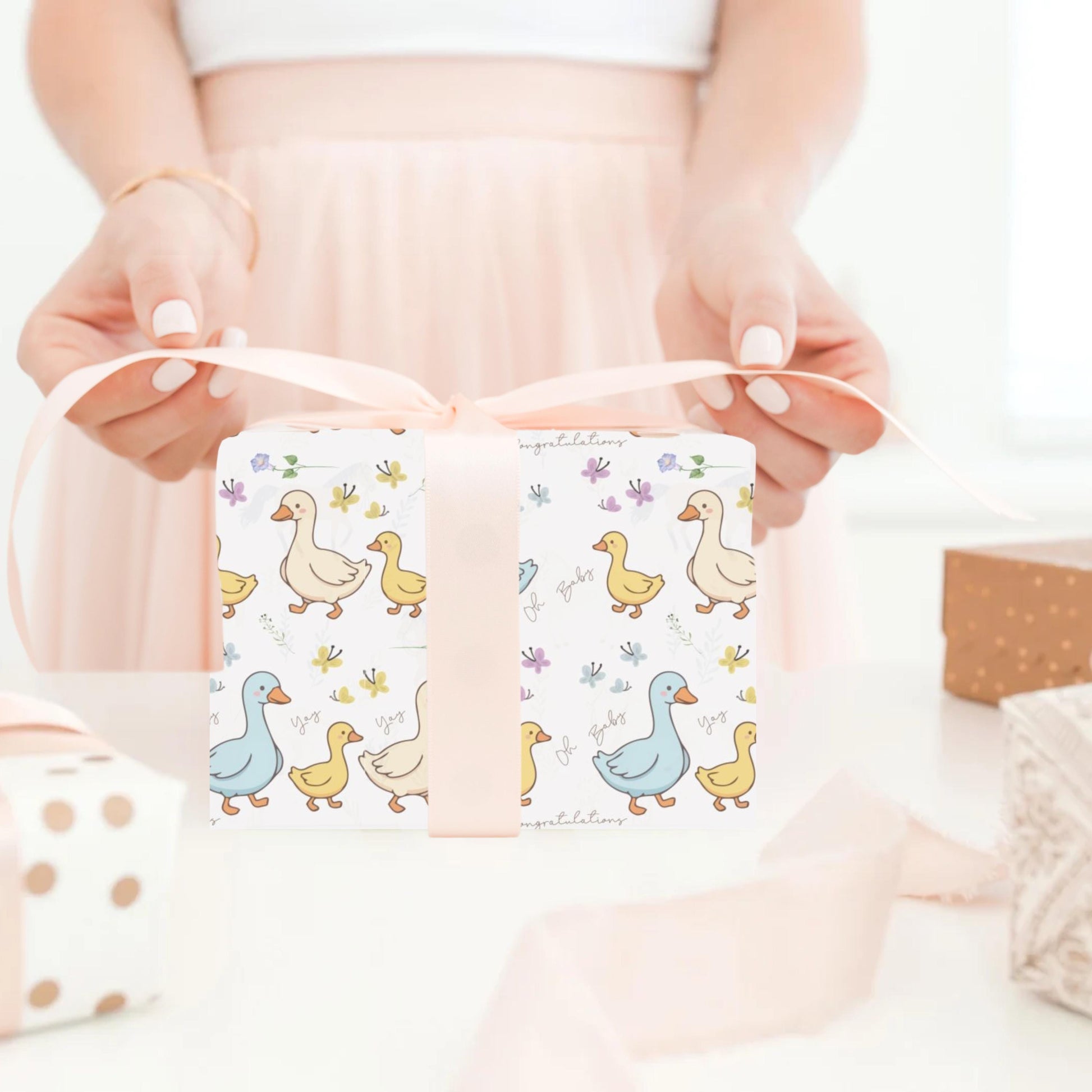 Cute duck baby shower wrapping paper with pastel ducklings and flowers wrapped around gift boxes