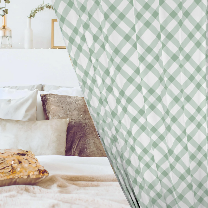 Green and white checkered curtain partially covering a bed with pillows and a wooden side table.