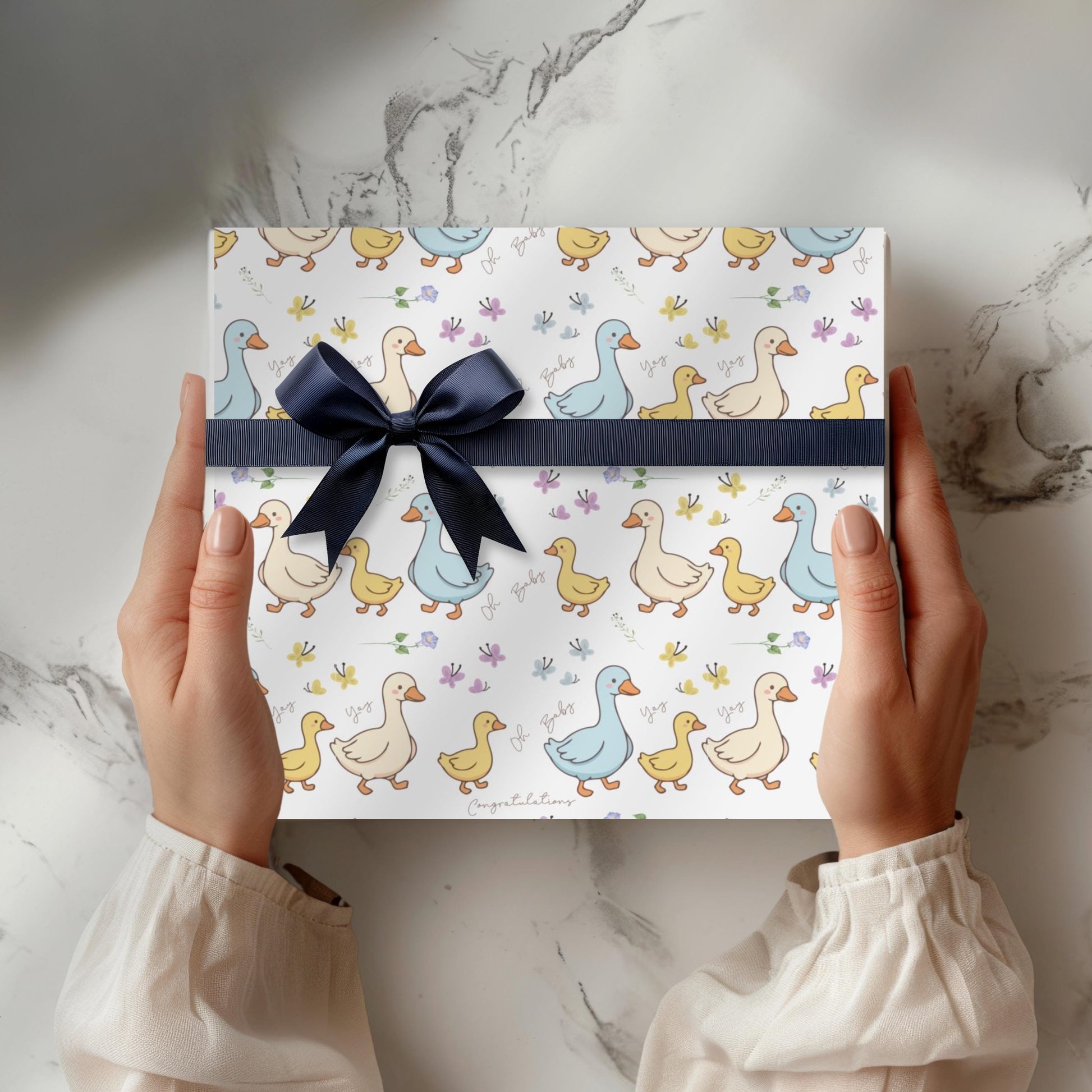 Cute duck baby shower wrapping paper with pastel ducklings and flowers wrapped around gift boxes